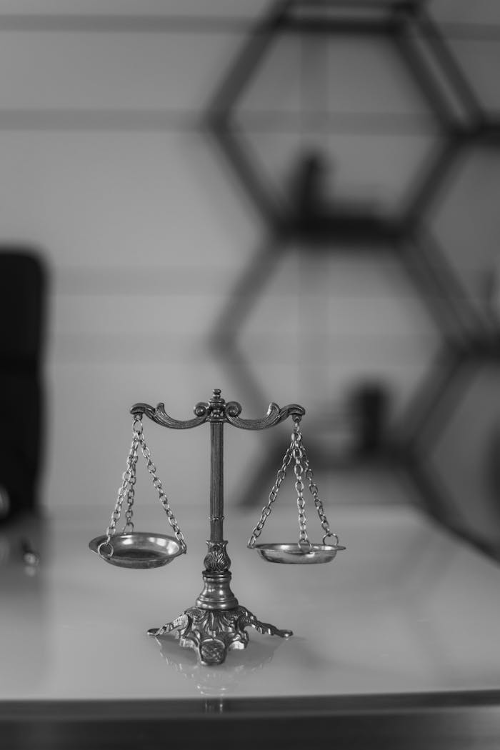 team-02 A black and white photo of a vintage balance scale in an office environment, emphasizing symmetry and justice.